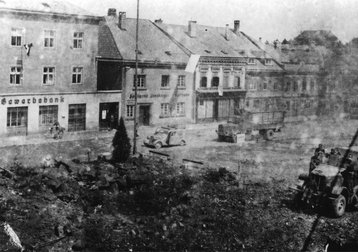 Die letzten Bomben haben am 8. Mai 1945 den Kilianbrunnen zerstört. Weiße Flaggen wehen von den Häusern und die letzten deutschen Soldaten verlassen die noch rauchende Stadt Richtung Westen. (Foto: Stadtarchiv Amstetten)