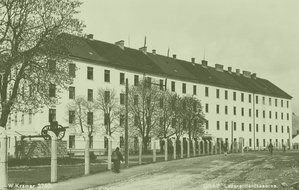 Eines der beiden Hauptgebäude mit dem Geschütz als Denkmal vor der Kaserne, die von einem Zaun umgeben ist. Aufnahme aus der Zwischenkriegszeit. (Bild: Archiv Rauchenbichler) 